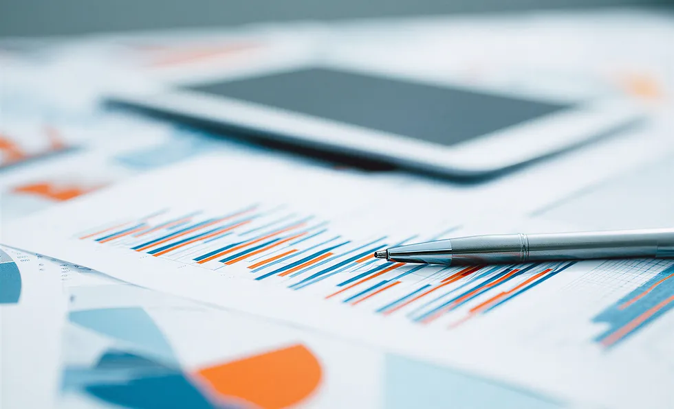 Pen lying on a printed bar chart with a blurred tablet in the background.