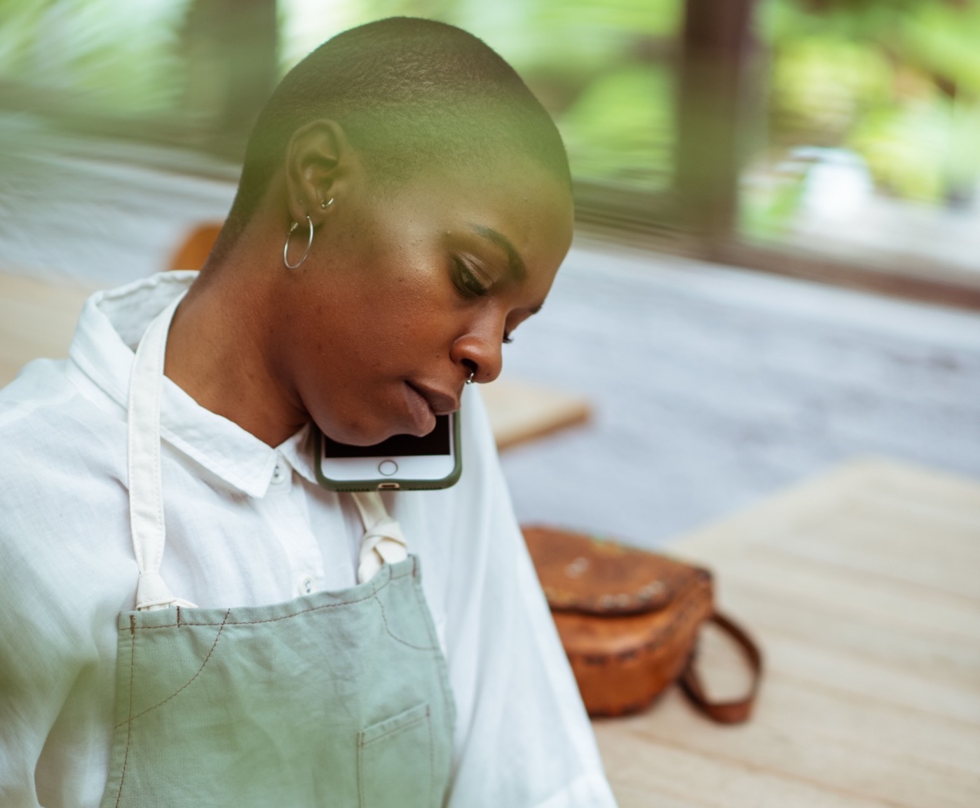 Une employée de restaurant en tablier, au téléphone, le combiné calé contre l'épaule